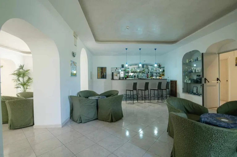 Bar interno con poltrone verdi e bancone illuminato