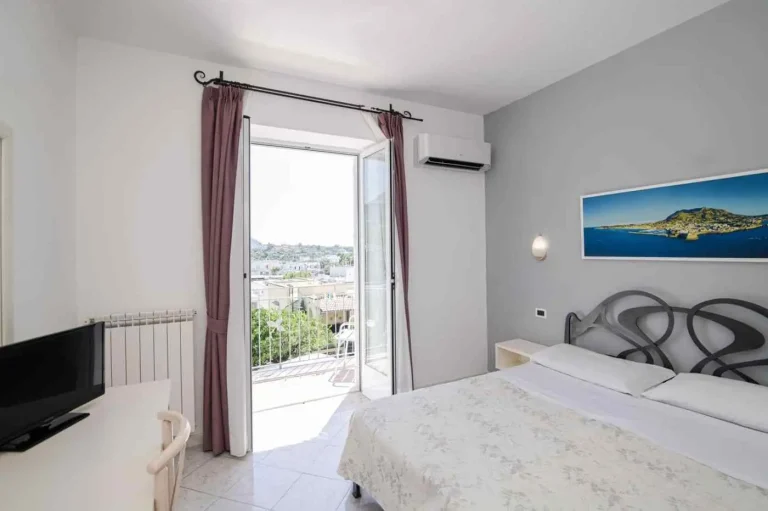 Camera con porta finestra aperta sul balcone e sulla vista di Forio