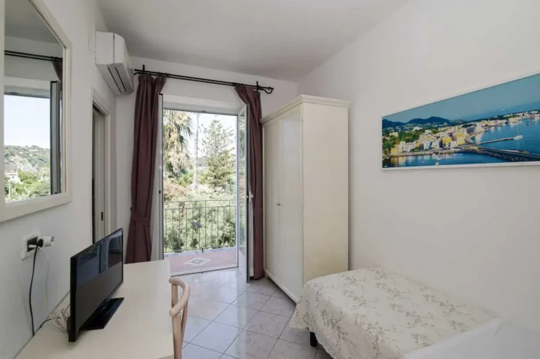 Camera singola con porta finestra aperta sul balcone e sul verde