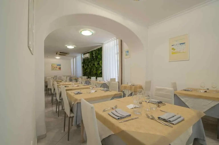 Sala del ristorante con i tavoli apparecchiati e la parete verde