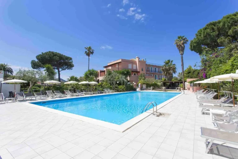 Solarium attrezzato con lettini e ombrelloni intorno alla piscina esterna